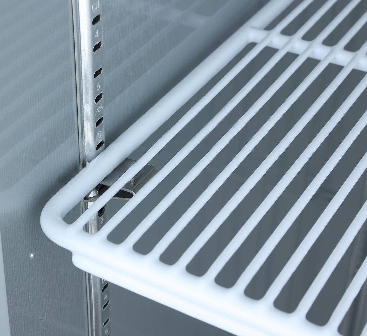 Close-up of an empty white wire shelf inside a refrigerator or storage unit, possibly an Atosa USA model. The metal rack is supported by adjustable brackets and shelf clips on a grooved vertical rail, allowing height customization. Background is smooth, light gray.