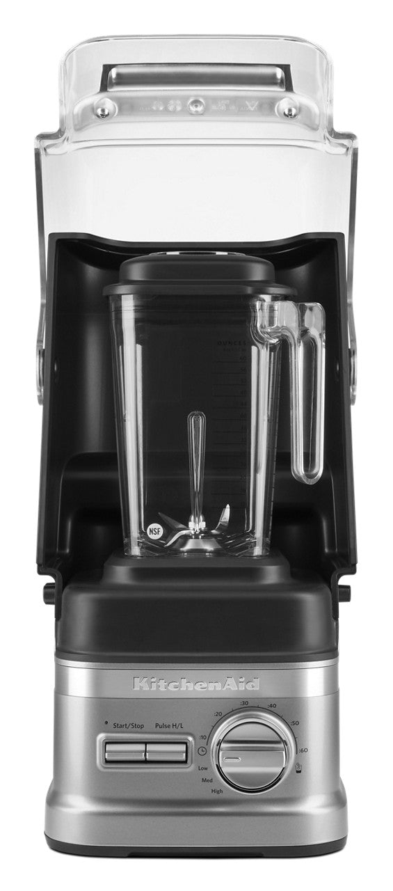 A silver and black KitchenAid Commercial Blender with a 60 oz. capacity features a clear plastic pitcher and handle, front-facing. It includes a control dial, several buttons, and an enclosure blender sound shield raised above the pitcher. Brand name visible on base.