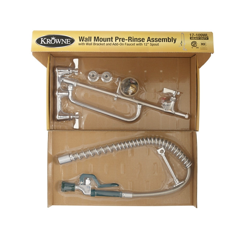 An opened box displays a Krowne wall mount pre-rinse assembly kit. Inside, shiny metal faucet parts and a hose with spray nozzle are neatly arranged in molded cardboard packaging. The yellow label details product info and features a barcode in the top right corner.