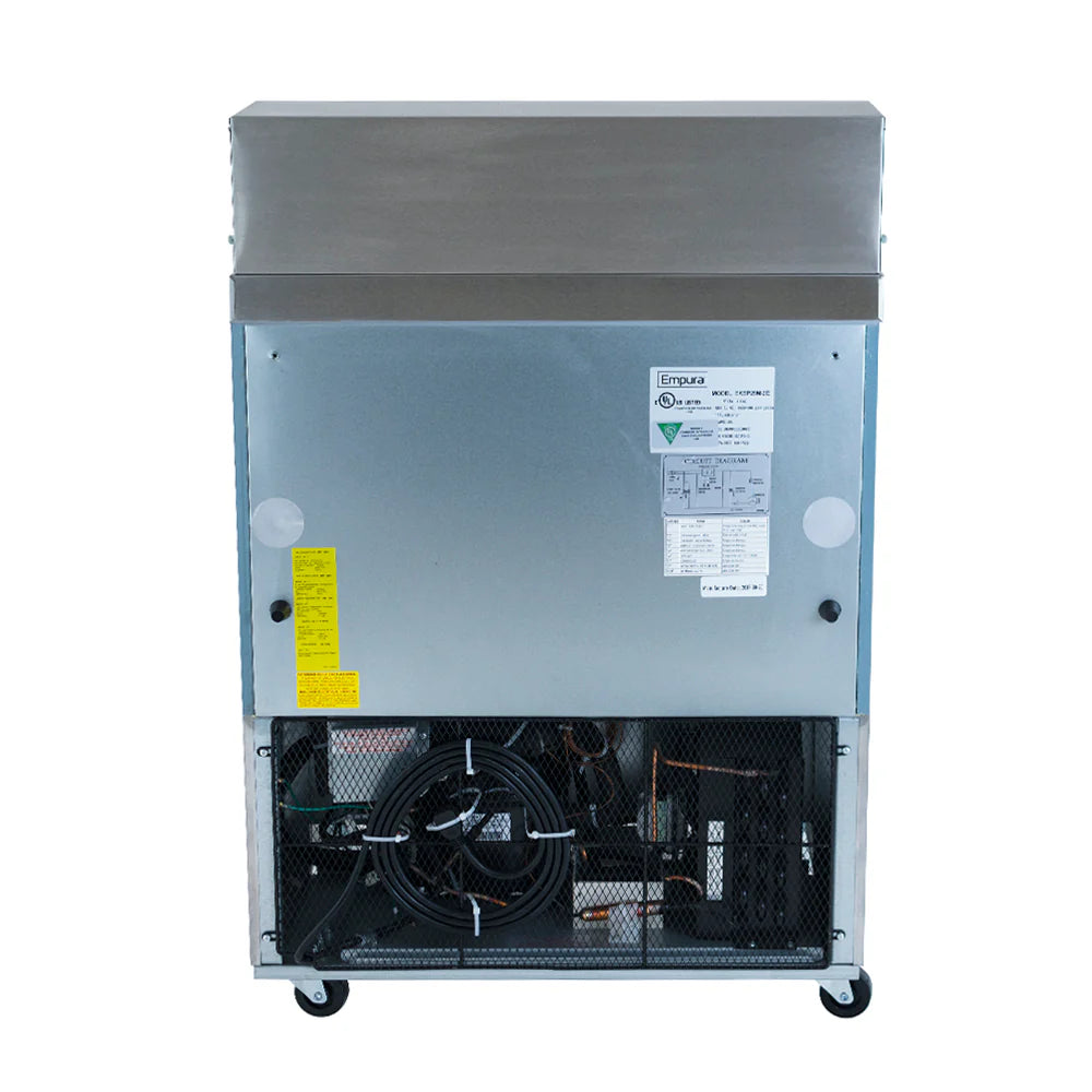 A commercial ice machine with a metallic finish is shown from the back, similar in style to a refrigerated sandwich prep table. The lower section features a black mesh panel revealing wiring and a cooling fan, while two small wheels sit at the base.