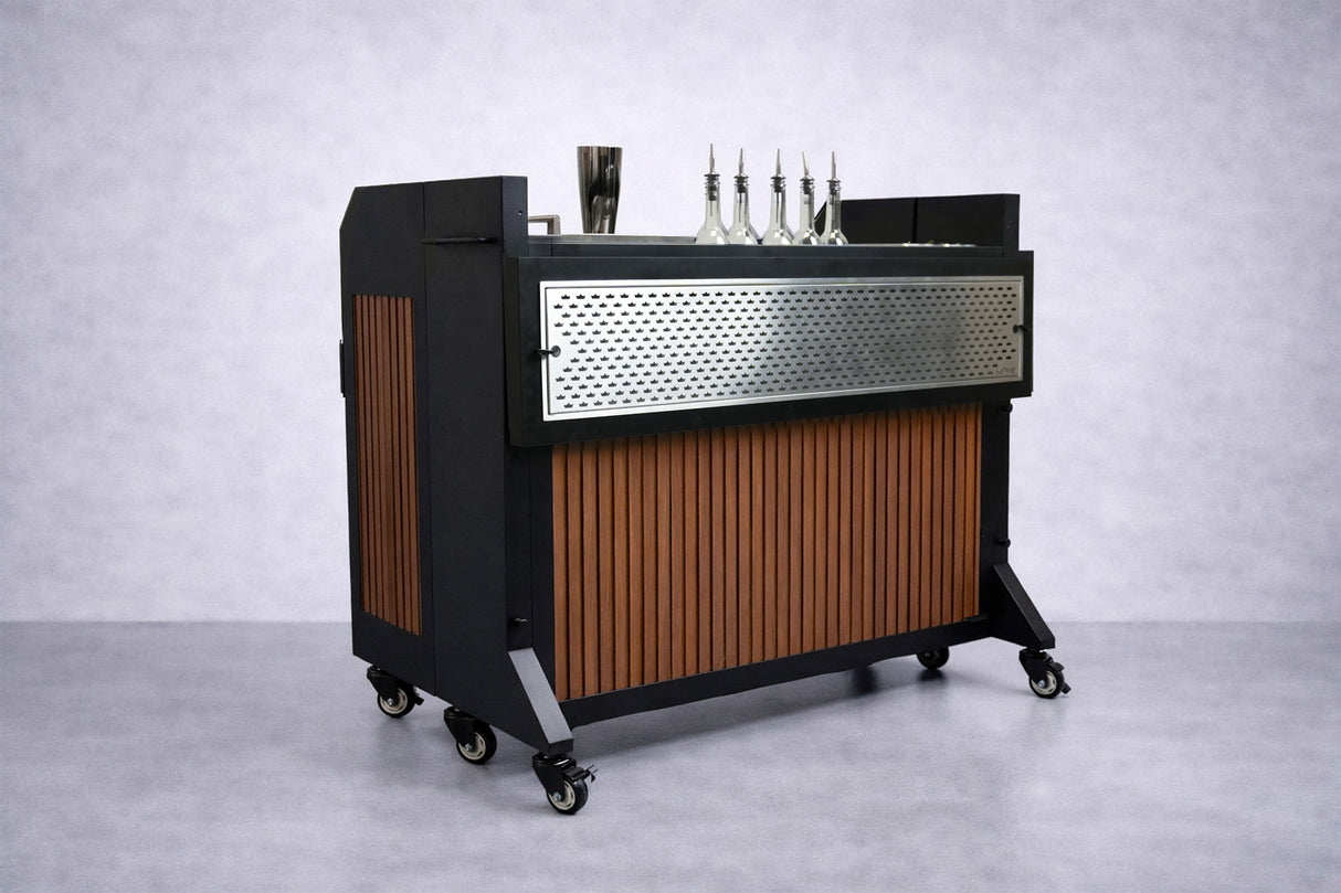 The NomadBar Mobile features a black metal frame, vertical wooden slats, and a perforated panel. Four caster wheels support the cart, which boasts an insulated ice bin on the countertop—perfect for keeping drinks chilled and tools close at hand.