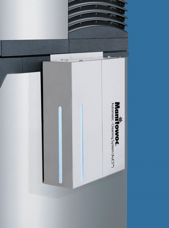 A close-up of a Manitowoc Automatic Cleaning System (AuCS) unit attached to an Indigo NXT Cubers appliance, against a blue background. The rectangular unit displays the Manitowoc logo and features two vertical blue indicator lights.