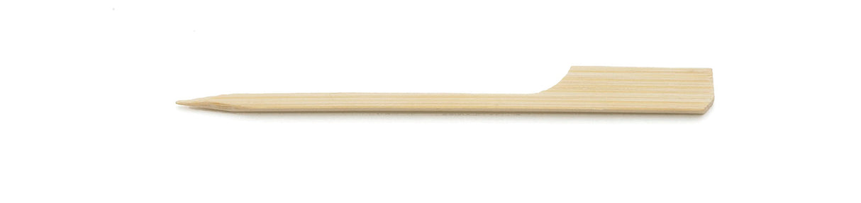 A single TableCraft Paddle Pick lies horizontally on a white background. Crafted from smooth bamboo, one end is pointed for piercing food while the other features a flat, paddle-shaped handle and light wood grain texture.