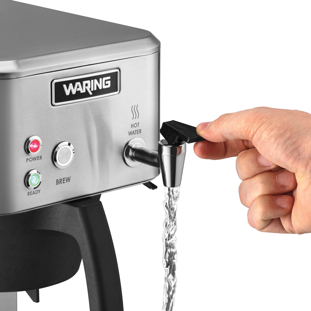 A hand turns on a black and silver hot water tap on a commercial coffee maker. Water flows from the tap, and indicator lights display power and ready status. The stainless steel coffee brewer surface is clean and shiny.