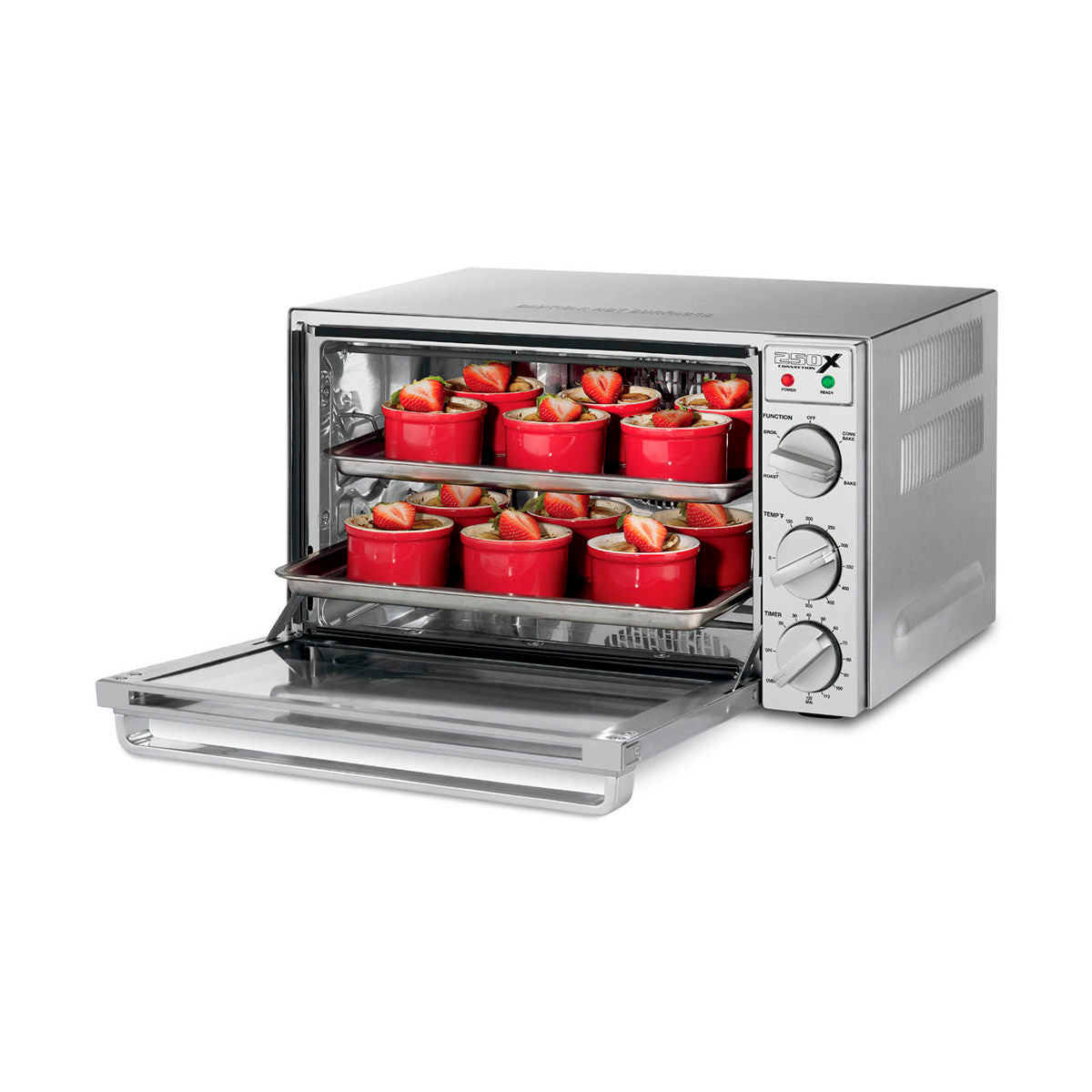 A silver commercial convection oven with its door open displays two trays of red ramekins on a quarter-size sheet pan, each filled with baked goods topped with strawberries and mint. Three control knobs and two indicator lights are on the front panel.