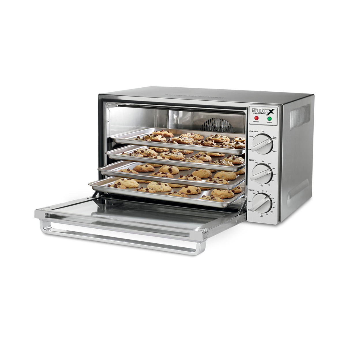 A stainless steel countertop oven with its glass door open reveals four racks filled with trays of chocolate chip cookies baking inside. This Commercial Convection Oven features control knobs and indicator lights on the right side.