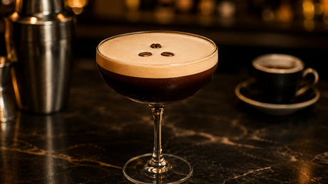 spresso martini in a chilled coupe glass with creamy foam and coffee bean garnish on a dark bar surface