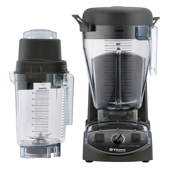 Two clear Vitamix XL Blender containers with black lids are shown, one upright on a commercial blender base with control knobs, the other resting on its side. Both containers feature measurement markings and metal blades visible at the bottom.