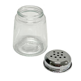 A modern glass cheese shaker jar with a wide opening sits next to its detached metal lid, which has multiple round holes for dispensing. Both the jar and dishwasher safe lid rest on a clean white background.