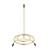 A brass plated paper towel holder from TableCraft Products with a vertical rod and three rounded legs tipped with black rubber ends. The minimal, modern design adds a sleek touch to any kitchen countertop.