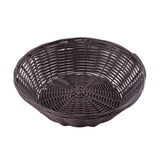 A round, empty, dark brown hand-woven wicker basket with a low rim and an open weave pattern is shown on a white background. The basket’s sides curve upward gently from the flat, tightly woven base.