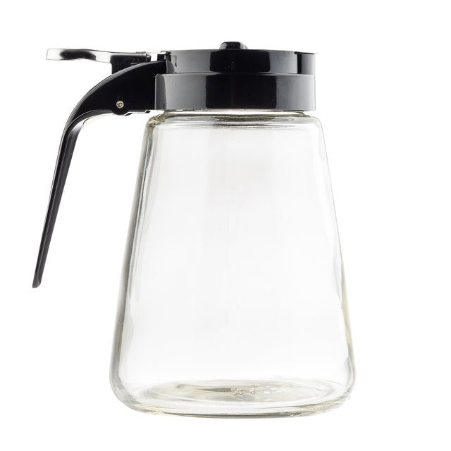 A clear, empty TableCraft Products Modern Glass Dispenser features a black plastic lid and handle. Its trapezoid shape has a wide base and narrower top, with a lever for pouring. Dishwasher safe, it’s set against a plain white background.