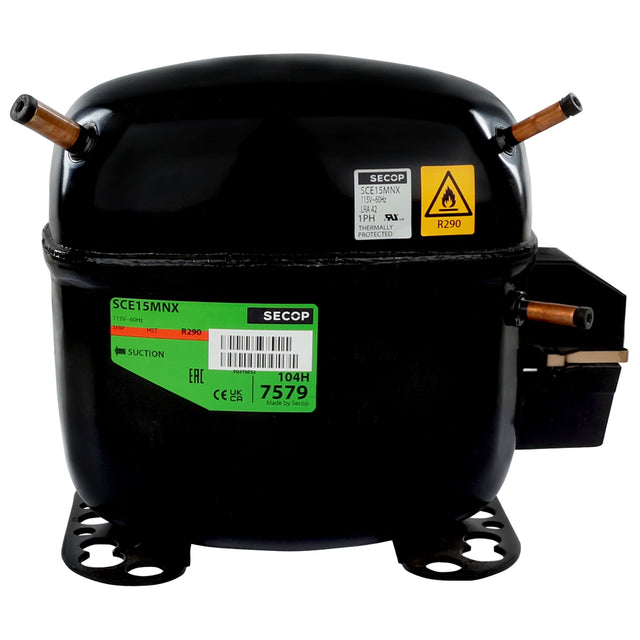 A black Secop compressor, used in Empura Ice Machines like the E-MCF430, features copper pipe fittings, green and yellow labels for model SCE15MNX and refrigerant R290, mounting feet at its base, and an electrical terminal cover on the right side.