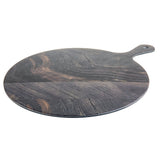 A round, flat, dark-colored wooden serving paddle with a handle featuring a small hole near the end. The wood grain is visible, showing natural variations in color and texture, reminiscent of a rustic barnwood pattern on a white background.