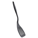 A black plastic slotted spatula with a curved, ergonomic silicone handle. The head has four long slots for draining, and the spatula is positioned diagonally on a white background.