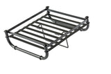A black metal luggage rack with horizontal slats and sturdy cylindrical legs, part of the industrial collection. Designed to hold suitcases or bags, it features a lower support bar and folded legs, set against a plain white background.