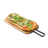 A rectangular flatbread pizza topped with fresh arugula, tomato slices, shaved cheese, and herbs sits on an acacia serving paddle with a black metal handle against a white background.