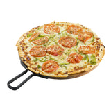 A round pizza topped with sliced tomatoes, green bell peppers, and melted cheese sits on a sleek TableCraft serving paddle with a black handle, against a white background. The crust is thin and slightly browned.