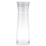 A tall, clear glass carafe with a slightly flared rim and narrow neck sits against a plain white background. Featuring a simple, minimalist design, this carafe comes with a strainer for easy gravity flow pouring.