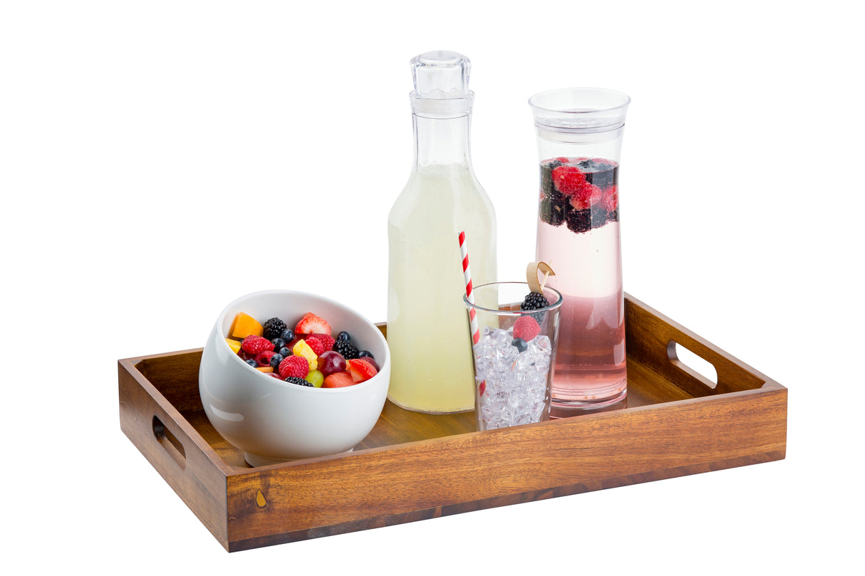 A wooden tray holds a bowl of mixed fruit, a bottle of lemonade, a glass of ice with a red-striped straw, and a tall 1-1/2 qt carafe of berry-infused water with floating berries. The white background makes the vibrant colors pop.