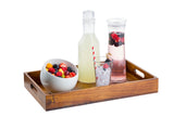 A wooden tray holds a bowl of mixed fruit, a bottle of lemonade, a glass of ice with a red-striped straw, and a tall 1-1/2 qt carafe of berry-infused water with floating berries. The white background makes the vibrant colors pop.