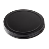A black, round, metal replacement lid with a smooth top surface and ribbed edges, viewed from an angle against a white background. Suitable for sealing jars or as a TableCraft beverage dispenser lid, it appears unused and clean.