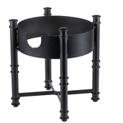 A black metal fire pit log holder with four cylindrical legs resembling bamboo and crossbars for support, inspired by the TableCraft Industrial Collection. The modern, sturdy design doubles as a beverage dispenser base for outdoor gatherings.
