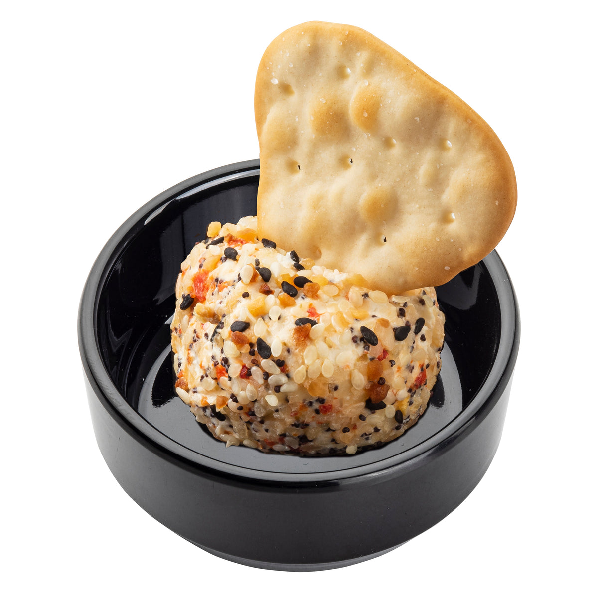 A round cheese ball coated with sesame seeds and spices sits in a black mini bowl. A single round cracker is inserted into the cheese ball. The background is plain white.
