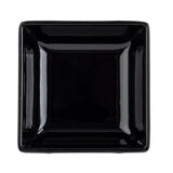 A glossy, black square bowl is photographed from above against a white background. The bowl has slightly raised edges and a minimalist design, reflecting light at the corners and sides, emphasizing its smooth and polished surface. Dishwasher safe bowl.