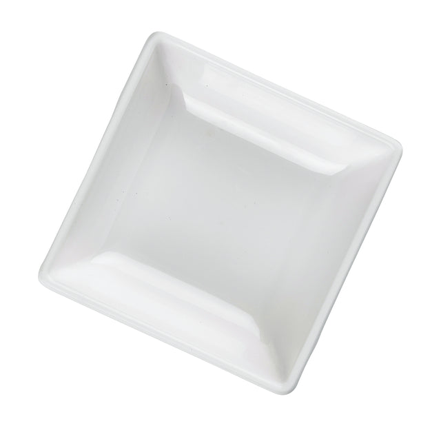 A square, shallow white ceramic dish, reminiscent of a mini melamine bowl, is shown at a slight angle on a plain background. Its smooth, glossy surfaces and gently rounded edges give it a clean and minimalist appearance. Dishwasher safe for easy care.