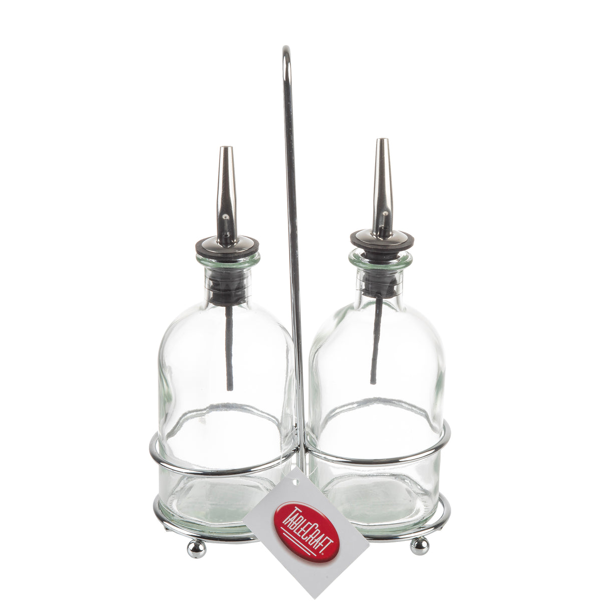 Two clear Oil & Vinegar Bottles with stainless steel pourers sit side by side in a chrome plated rack. A white tag with a red TableCraft logo hangs from the stand, all set against a plain white background.