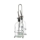 Two clear Oil & Vinegar Bottles with stainless steel pourers rest in a chrome plated rack with a handle and round feet. The bottles are empty, showcasing a minimalistic setup against a white background.
