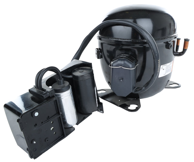 The E-EGM-23FB Compressor for Empura Refrigeration features a black cylindrical design with attached electrical components, capacitor, and wiring on a metal base. Two copper pipes extend from one side and a protective cover shields the terminal connections.