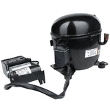 A black Empura Refrigeration compressor with a cylindrical shape is shown connected to an electrical component by a thick black cable. Both parts have labels with text and diagrams. The compressor has metal mounting feet and a copper pipe outlet.