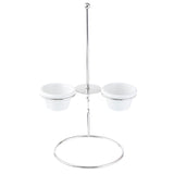 A stainless steel stand with a central pole and circular base holds two small white ceramic bowls in ramekin holders on opposite sides. The minimalist, modern design is perfect for serving sauces or dips alongside an onion ring tower.