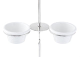 Two white ceramic cups with metal rims are held in a shiny stainless steel stand with a central pole and round base. The setup, reminiscent of ramekin holders, is viewed from above on a completely white background.