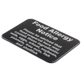 A wall mounted rectangular black warning sign with bold white text reads: “Food Allergy Notice. Please be advised that food prepared here may contain these ingredients: milk, eggs, wheat, soybeans, peanuts, tree nuts, fish, and shellfish.”.
