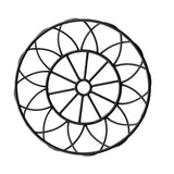 A round black metal trivet with a geometric, floral-inspired design features interlocking petal-like shapes and a striking black powder coat finish. The symmetrical pattern adds decorative charm, photographed on a white background.