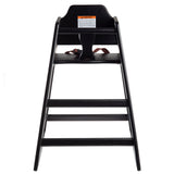 A stackable black wooden high chair viewed from the front. It features a seat with a safety strap, a high backrest with a warning label, and two horizontal footrests. The chair’s sturdy wood design is ideal for young children.