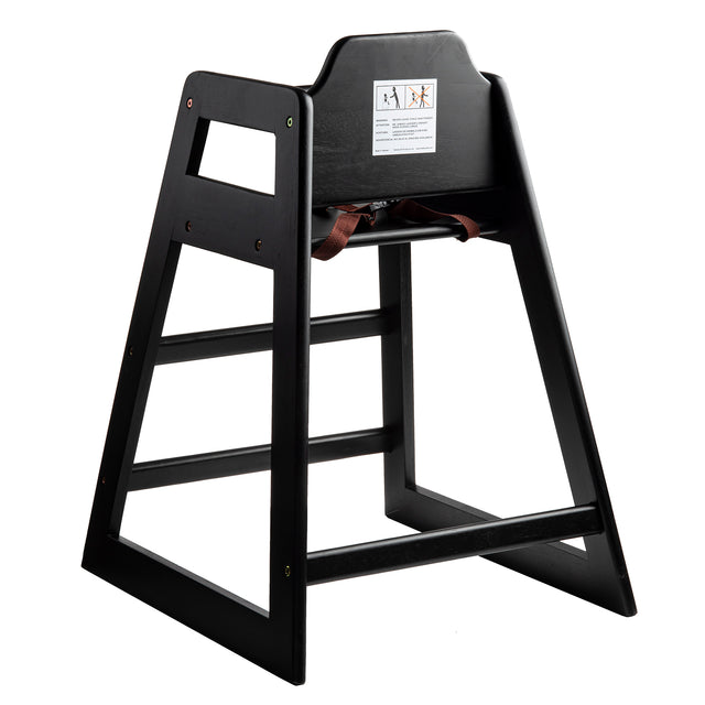 A stackable black wood restaurant-style high chair featuring an open-frame design, safety strap, and warning label on the backrest. Angled for stability, it's perfect for seating young children at tables.