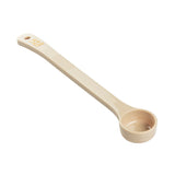 A beige Spoonout measuring spoon made of durable polycarbonate with a long handle. Labeled 1.5 TBSP / 22.5 mL in yellow, it features a deep, round bowl for scooping and a hole at the tip for hanging.