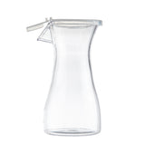 A clear, empty glass carafe with a flared body, narrow neck, and a hinged polypropylene lid. The carafe stands upright against a plain white background, showcasing its simple, modern design.