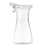 A clear, empty polycarbonate carafe with a flared base and narrow neck, topped by a hinged, see-through polypropylene lid. Photographed on a white background, it highlights the carafe’s simple, modern design and transparent material.