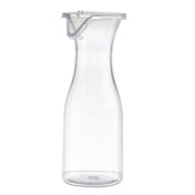 A tall, clear 19 oz polycarbonate carafe with a narrow neck and flared rim is shown upright against a white background. The carafe includes a transparent plastic lid with a metal clasp. Its overall design is simple and modern.