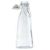 Tall, clear glass carafe with a wide base narrowing toward the top, featuring a metal swing-top clasp and a white ceramic stopper. This 34 oz carafe stands empty and upright against a plain white background.