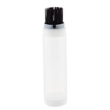 A clear plastic squeeze bottle with a white ValveTop cap stands upright. The cap features an attached bundle of short, black bristles, resembling a built-in brush. The empty squeeze bottle is set against a plain white background.