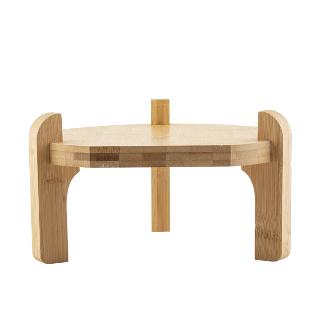 A small, round bamboo stool with two thick, curved legs and a vertical back support. Its minimalist TableCraft design shows visible wood grain, making it perfect as a beverage dispenser stand, photographed against a plain white background.