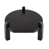 A round, black pinewood platform with three thick, angled legs and a small vertical tab at the back, set against a white background. The surface appears smooth, and the design is minimalist and modern—a stylish beverage dispenser stand by TableCraft.