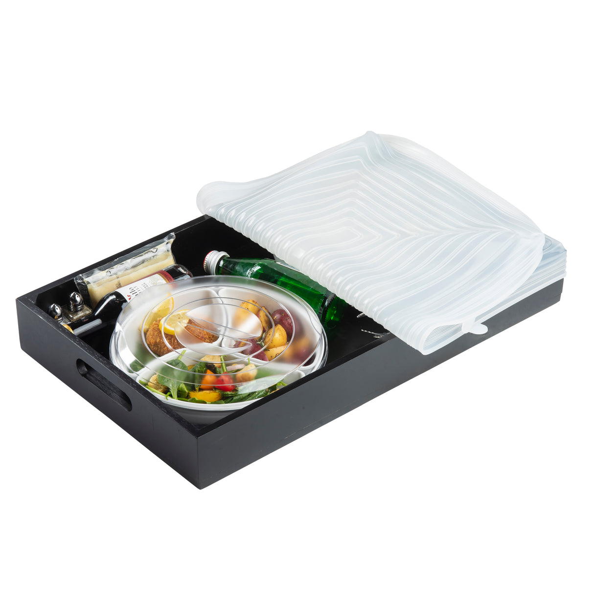 A black serving tray holds a lidded metal plate with assorted food, a green glass bottle, a small wine bottle, packaged cheese, and utensils. A TableCraft 10776 silicone crate cover is partly placed over the tray to protect the contents.