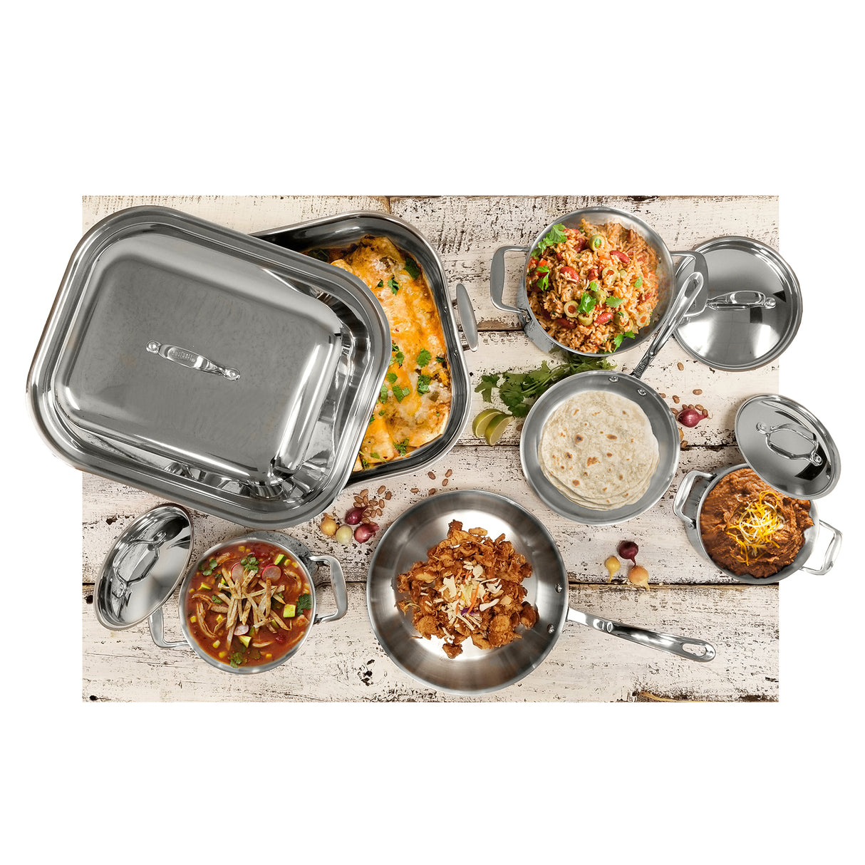 A variety of cookware from the Signature Cookware Set, crafted with a sleek stainless steel finish, is filled with colorful dishes—baked casserole, seasoned rice, chili, tortillas, and cheese—artfully arranged on a rustic white wooden surface.